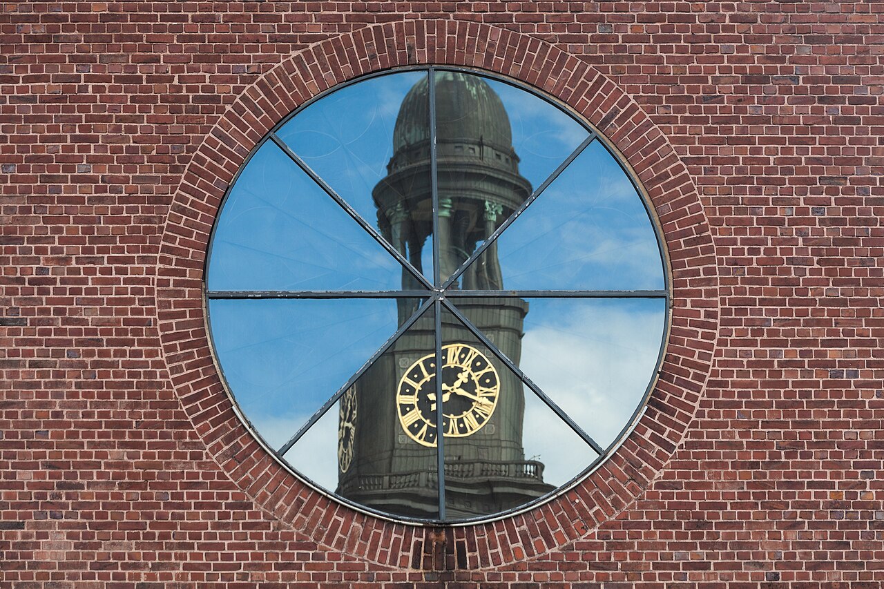 St. Michaelis reflejado en un ventanal circular de ladrillo en Hamburgo